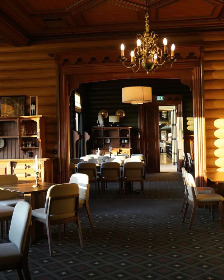 Dining room with wooden walls, a chandelier and laid tables