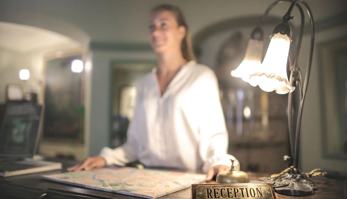 Front desk in the evening, a table lamp glowing above the reception counter