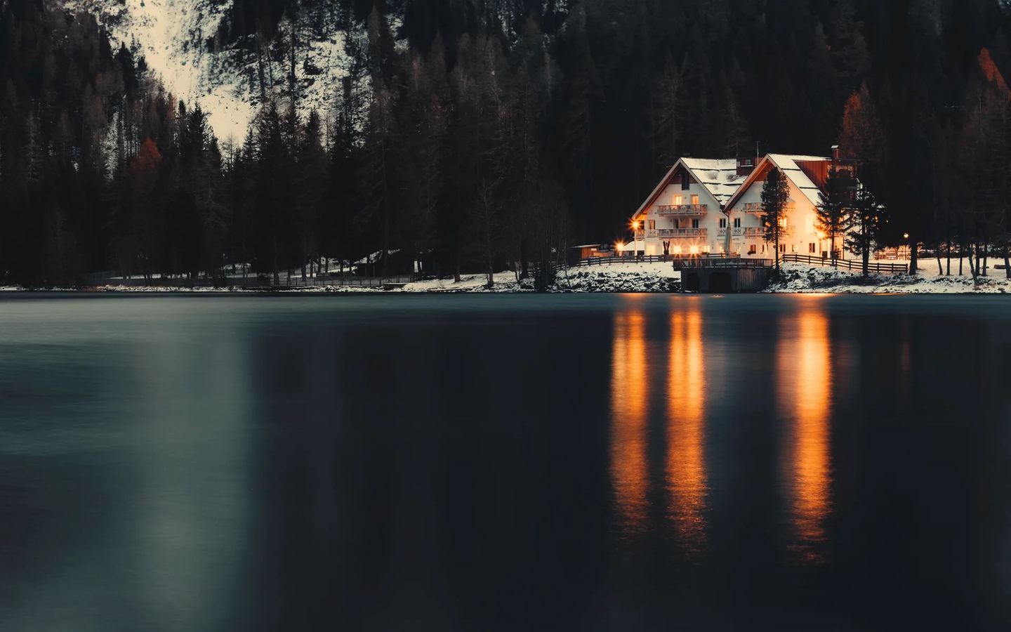 Country hotel on a lake at dusk, its windows lit