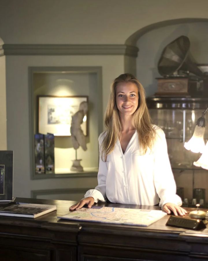 Host at a wooden front desk in the light of a table lamp